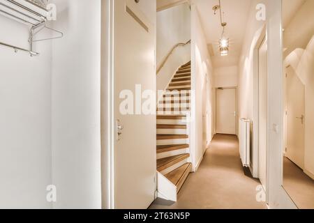 Interior of empty illuminated hallway with wooden steps leading to upper floor and doors of different room at modern house Stock Photo