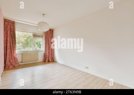 Interior of empty living room with red curtains on large window and light hanging on ceiling in unfurnished house Stock Photo