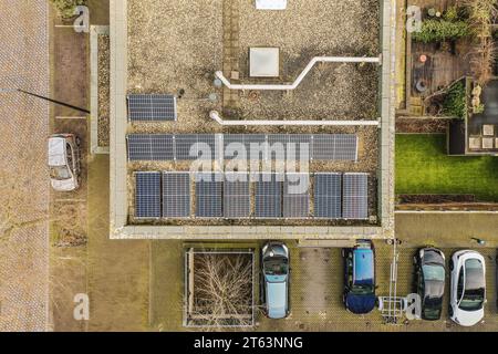 Aerial view of solar panels installed on apartment building rooftop and cars parked in parking lot Stock Photo