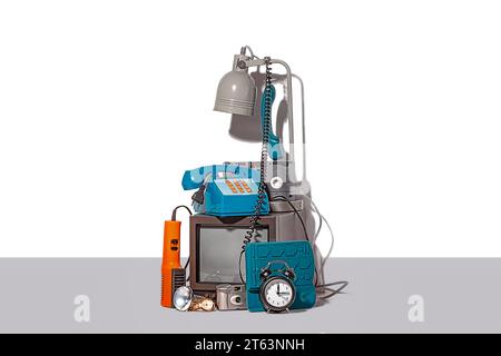 A curated collection of vintage technology items against a white backdrop, featuring an old television, rotary telephone, alarm clock, desk lamp, and Stock Photo