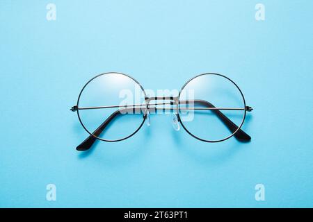 Glasses in round thin metal frame isolated on blue surface. Stock Photo