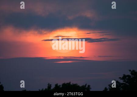 The red sun rising behind clouds in summer, Vienna (Austria) Stock Photo