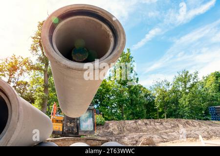 Big diameter concrete pipes for drainage works delivered on construction site and offloaded by excavator Stock Photo