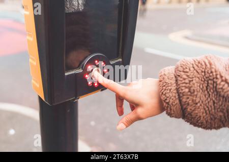 woman crossing road and pressing the traffic light button Stock Photo