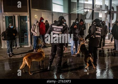 Michael Bunel/Le Pictorium - Exile in the land of human rights - 19/11/2020 - France/Ile-de-France (region)/Paris - Two men in charge of security at the Rosa Park shopping complex come to intimidate the refugees with their dogs and ask them to leave. Local residents complain that the return of refugees to this distribution point is becoming a fixture. The two security guards come at the request of the center's director. November 19, 2020. Paris, France. In October 2015, the municipality presented eighteen commitments in a document entitled 'Mobilizing the Paris community to welco Stock Photo