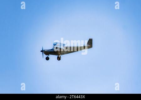 small airplane flying on blue sky, side view with some clouds Stock Photo