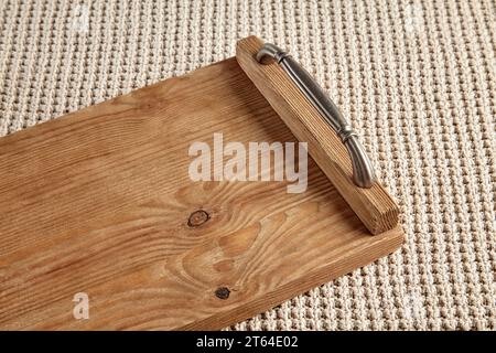 Handmade brown wooden tray with brass handles on a beige knitted tablecloth texture Stock Photo