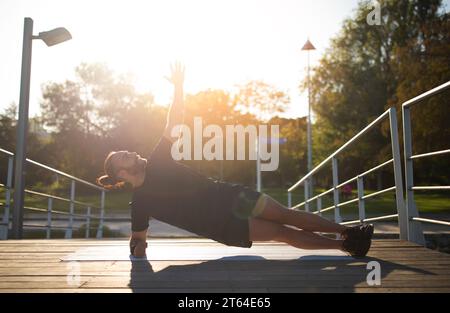 Sporty Young Man Doing Side Plank Exercise While Training Outside Stock Photo