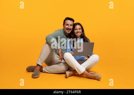 Happy senior european man and lady sit on floor with laptop, watch video Stock Photo