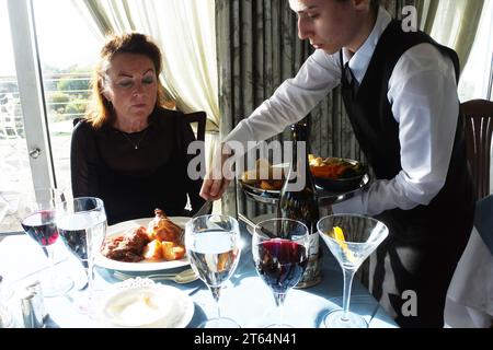 Mature female being served dinner at a luxury hotel - John Gollop Stock Photo