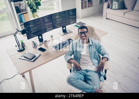 Photo of young data analyst in it company man sitting comfortable boss chair relaxing after good job done in office workspace background Stock Photo