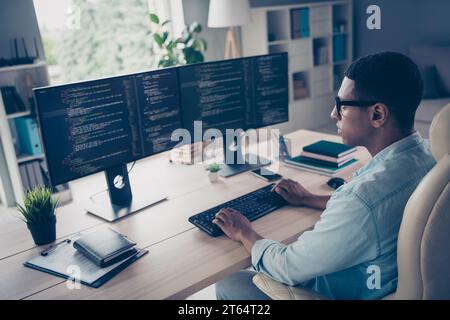 Close up side profile photo of professional young guy it specialist create code looking two modern monitors typing keyboard stay in office Stock Photo