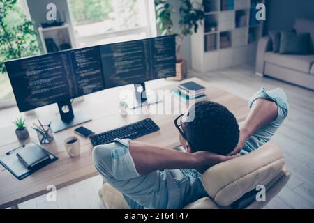 Side view photo of relaxing young funny guy lying comfortable armchair in office while reviewing his website code app indoors workplace Stock Photo