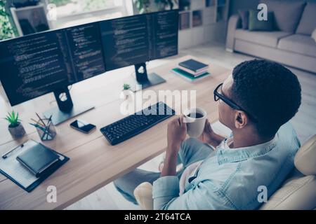 Rear back view photo of young boss man drinking coffee every morning he reviewing his juniors programmers code isolated on home workshop Stock Photo