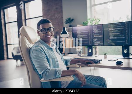 Portrait of young smiling guy sitting armchair smart senior devops professional programmer control cyber security at work place in office Stock Photo