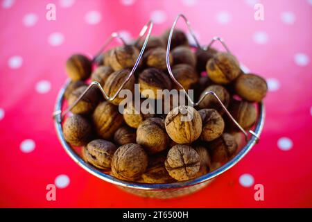 A bowl full of walnuts on a red tablecloth with white dots. Stock Photo