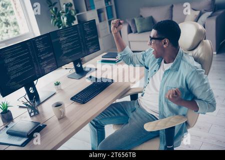 Photo of sitting comfortable armchair guy professional it specialist celebrate he optimized software works correct open space indoors Stock Photo