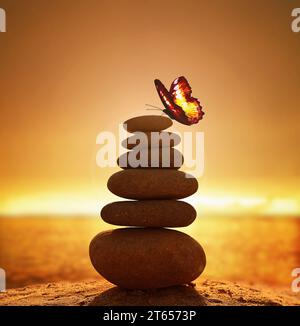 Balanced pebble pyramid silhouette on the beach on sunset. Sea on the background. Zen stones on the sea beach, meditation, spa, harmony, calmness, bal Stock Photo