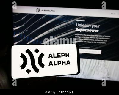 Person holding cellphone with logo of German artificial intelligence company Aleph Alpha GmbH in front of webpage. Focus on phone display. Stock Photo