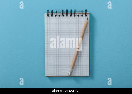 Blank Сheckered Notepad With Wooden Pencil On Blue Background Stock Photo