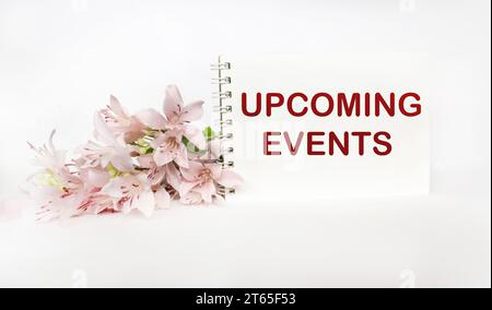 Concept for message about upcoming events on a notepad, with a flower. Stock Photo