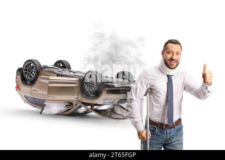 Man with an injury gestruing thunbs uo and an upside down SUV with smoke and broken windows isolated on white background Stock Photo