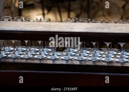 Rows of empty, clean wine glasses, backlit and arranged on a bar for drink service at a wedding celebration. Stock Photo