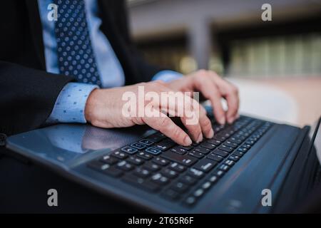 Close up business man hands typing on laptop computer keyboard, online remote working or searching information, sending e-mails or messaging sitting outside. Unrecognizable entrepreneur using internet. High quality photo Stock Photo