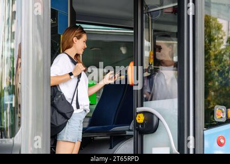 Woman contactless pays for a ticket for public transport in a tram ...