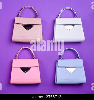 Flat lay of four trendy leather women's top-handle bags of the same design but different colors on a purple background. Fashion blog or magazine. Choo Stock Photo