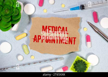Medical appointment. text on white paper, blue background, near pills and stethoscope in blue Stock Photo
