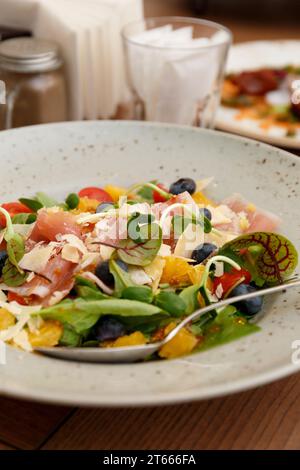 Salad with jamon, prosciutto, parmesan, cherry tomatoes, blueberries in a restaurant, close-up. Healthy, proper nutrition, healthy products. Stock Photo