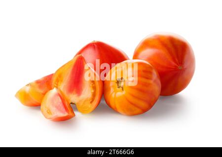Whole and cut large organic striped yellow-red tomatoes isolated on white background, close-up Stock Photo