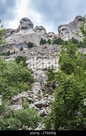 Carved granite busts of George Washington, Thomas Jefferson, Theodore Teddy Roosevelt and Abraham Lincoln framed by trees at Mount Rushmore Stock Photo