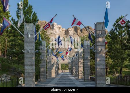 Carved granite busts of George Washington, Thomas Jefferson, Theodore Teddy Roosevelt and Abraham Lincoln above the Avenue of Flags at Mount Rushmore Stock Photo