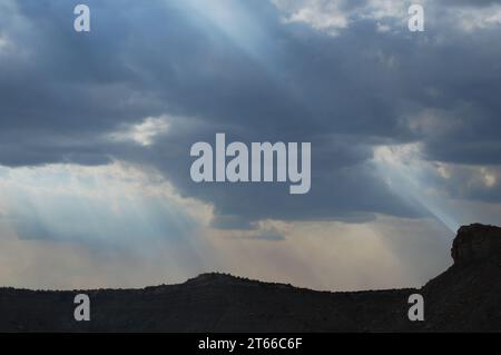 Rays of sunshine beam down on the canyons, mesas, and deserts of South Central Utah, as storm clouds gather on an October afternoon. Stock Photo