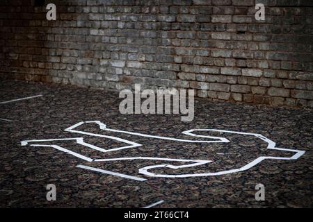 A white tape chalk outline in the shape of a dead body. Stock Photo