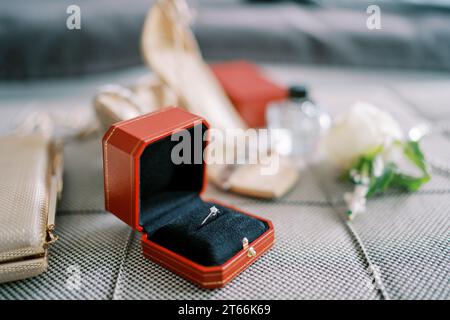 Wedding ring in a red box lies on the sofa next to the bride clutch Stock Photo