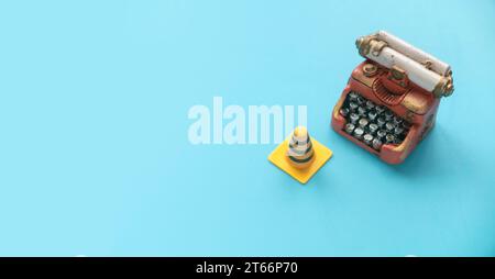 Fixing, maintenance and under construction concept.  Miniature typewriter and traffic cones on blue background. Stock Photo