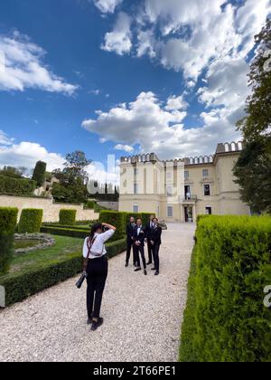 Rome, Italy - 09 august 2023: Girl photographer photographs the groom with his friends in the garden of an old villa Stock Photo