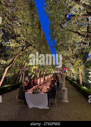Rome, Italy - 09 august 2023: Guests are sitting at the laid festive table on the alley in the garden near the outdoor gas heaters Stock Photo