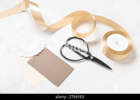 Golden satin ribbon, scissors and greeting card on white background Stock Photo