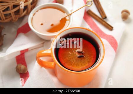 Cup of hot mulled wine with orange and bowl of honey on white background Stock Photo