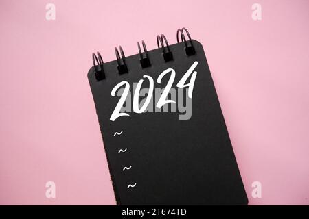 New year resolutions 2024 on black spiral notebook. 2024 goals list with notebook. Resolutions, plan, goals, action, checklist, idea concept. New Year Stock Photo