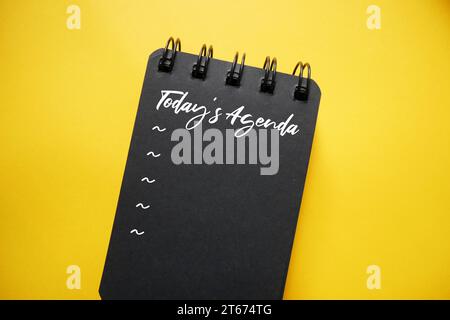 Black spiral notebook written with Today's Agenda on yellow background with copy space. Stock Photo