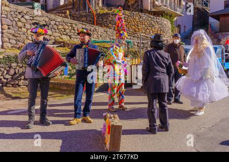 Valfloriana, Italy - February 26, 2022: Carnival participants costumed as bride and groom, and musicians, in the Valfloriana carnival, Trentino, North Stock Photo