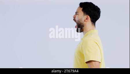 Scream, angry and man in studio at mockup space for crisis, conflict and mad emoji reaction on white background. Profile of frustrated indian model Stock Photo