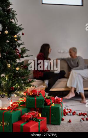 Beautiful Christmas gift boxes on floor near Christmas tree and have people background in room Stock Photo