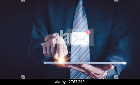 Businessman holding tablet and touching with virtual white newsletter for electronic mail or E-mail with notification alert concept. Stock Photo