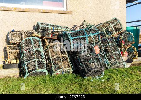 Traditional lobster pots or crab pots stacked up on the quayside in the fishing village of Caithness, Scotland Stock Photo